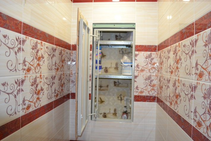 Красно-бежевый туалет с узорами на плитке и скрытым шкафом