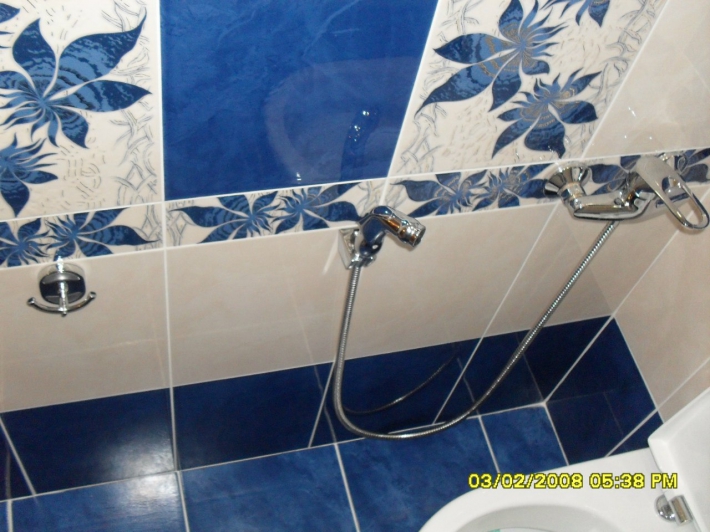 Туалет с сине-белой плиткой и гигиеническим душем возле унитаза