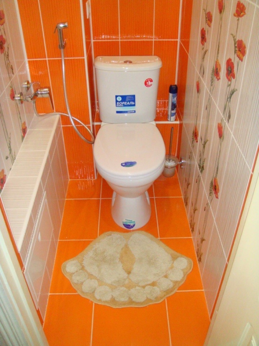 Оранжевый маленький туалет с гигиеническим душем и коробом для труб