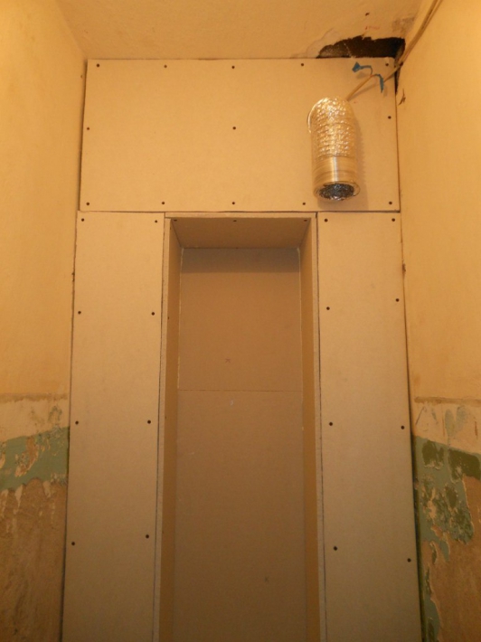 Небольшой туалет с гипсокартонными стенами, рулонной шторой и нишей для хранения за унитазом