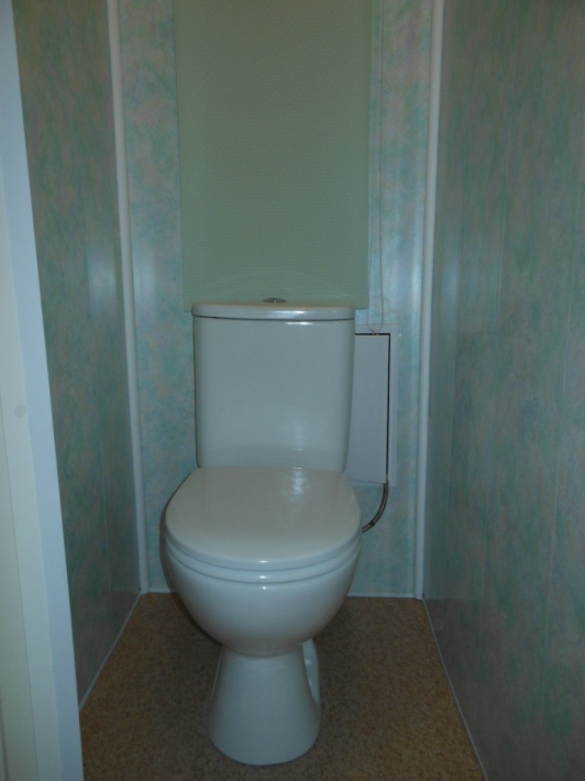 Небольшой туалет с гипсокартонными стенами, рулонной шторой и нишей для хранения за унитазом